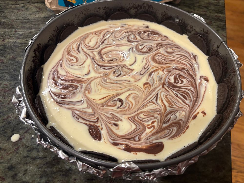 An unbaked chocolate cheesecake surrounded by Oreos in a spring form pan. 