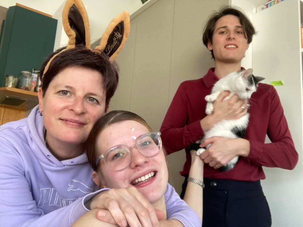 Familienfoto zu Ostern - mit zwei erwachsenen Kindern und einer Babykatze. Die Mutter trägt Hasenohren.