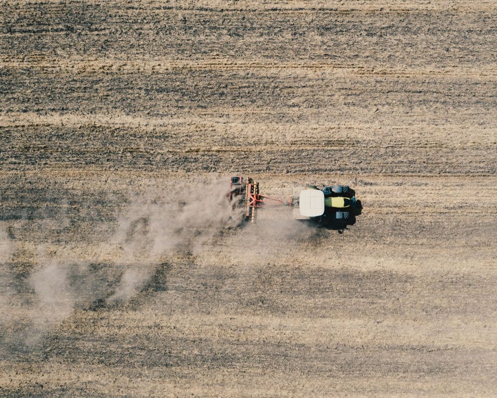 Tractor applying pesticide to a barren field. Photo by Bence Balla-Schottner on Unsplash