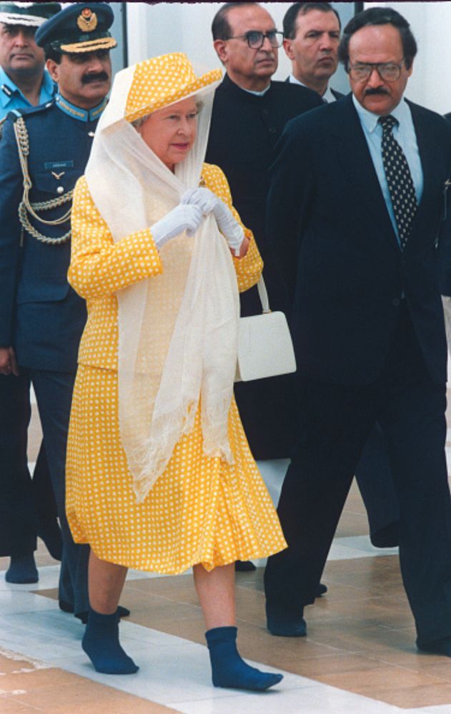 Queen Elizabeth II, wears a scarf over her hat to cover her hair and walks in socks without shoes as a sign of respect as she visits the Shah Faisal Mosque on October 07, 1997 in Islamabad, Pakistan.