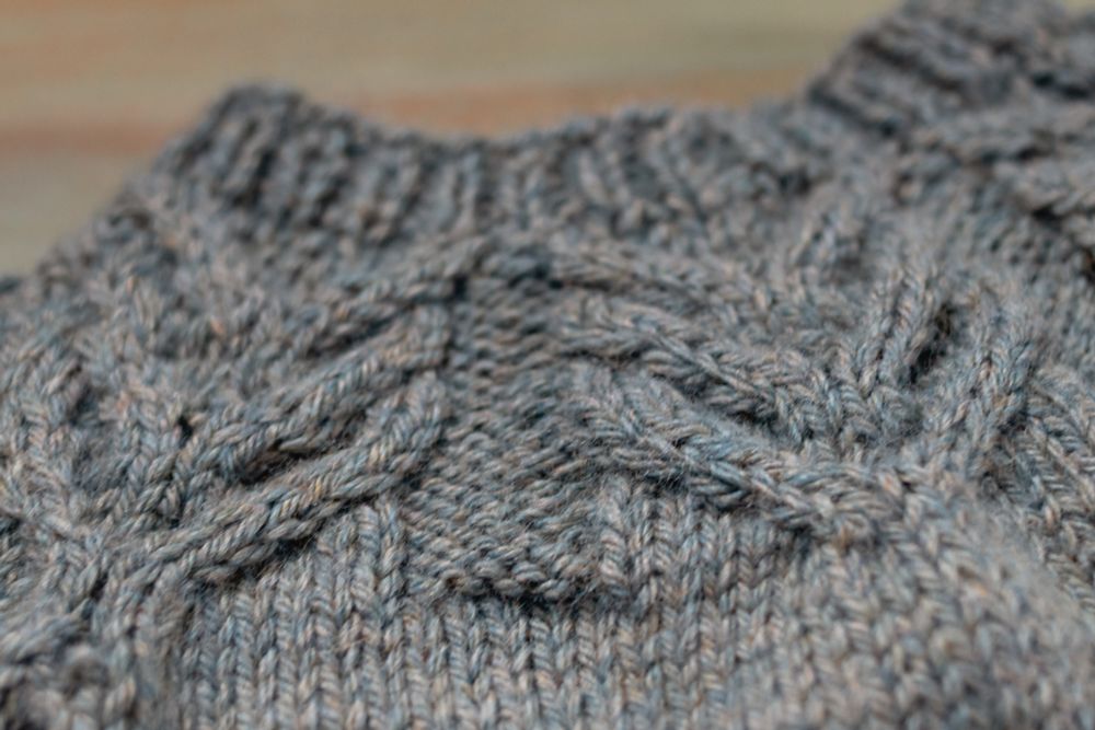 A close-up of the cabled yoke on a gray-green sweater