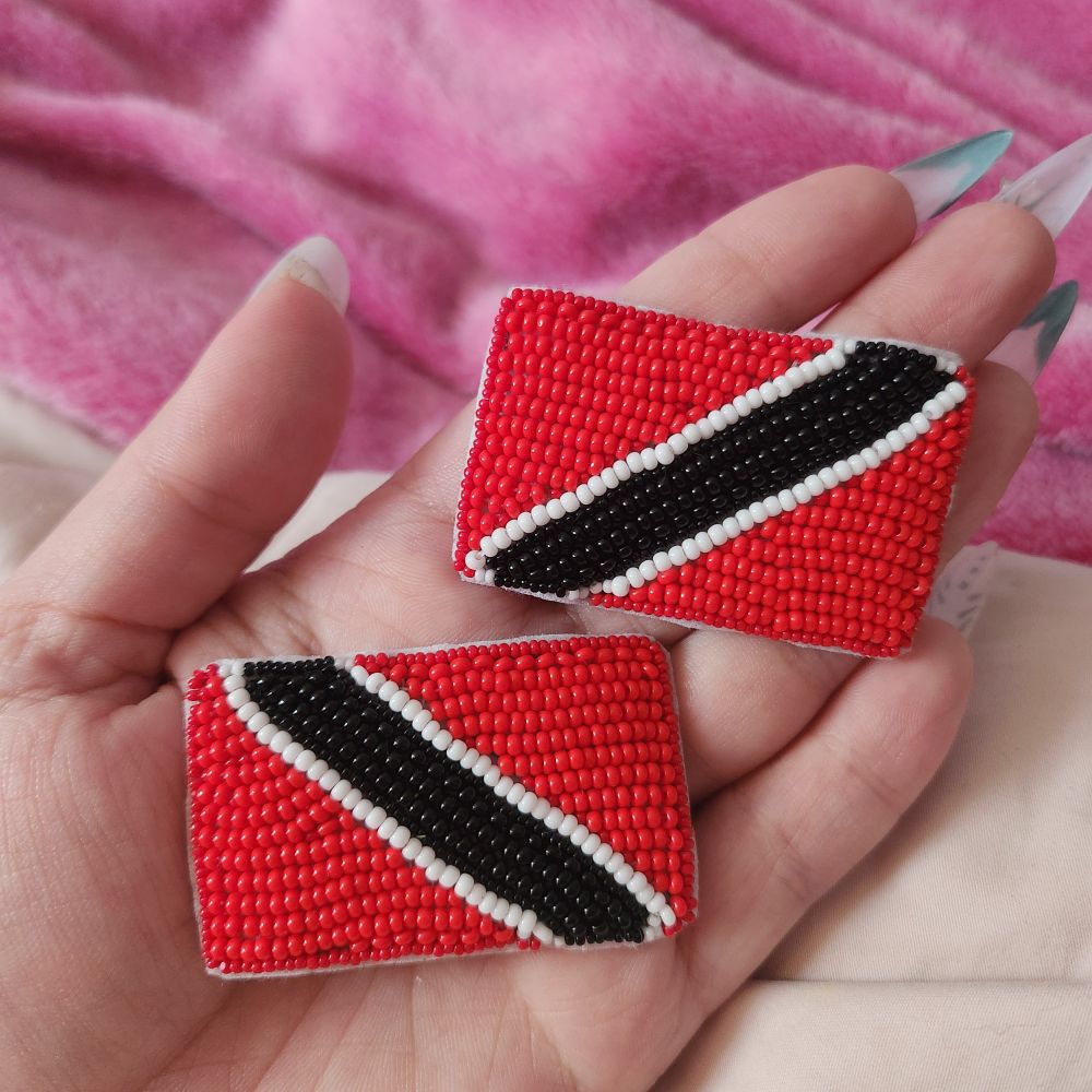 Flat beaded version of the Trinidad and Tobago flag, it is a red flag with a black stripe diagonally across it with two small white stripes on either side of the black. 