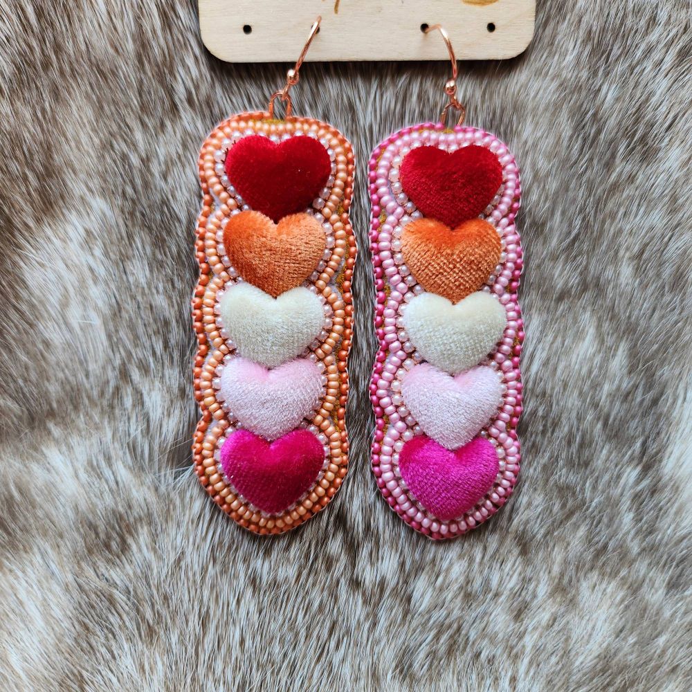 Velvet heart cabachon earrings in the lesbian flag colours, they are surrounded by pearl rhinestone banding one half of the earrings are beaded with metallic light and dark pink, the other is light and dark orange. 