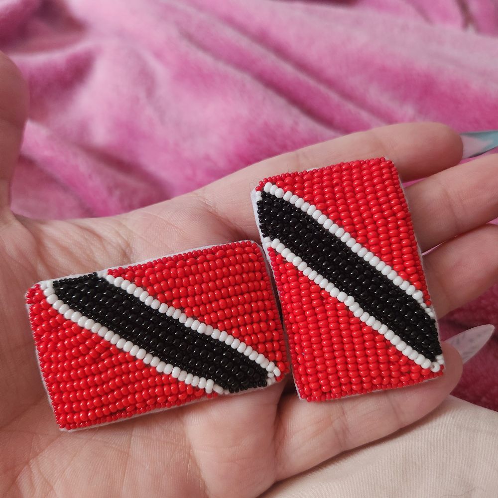 Flat beaded version of the Trinidad and Tobago flag, it is a red flag with a black stripe diagonally across it with two small white stripes on either side of the black. 