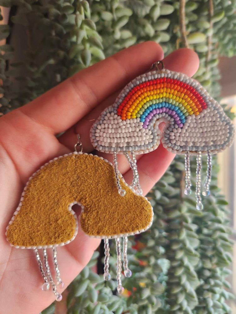 Beaded rainbow earrings, they have beaded raindrops hanging from their clouds. You can see the back of the earring is brown tanned moosehide. 