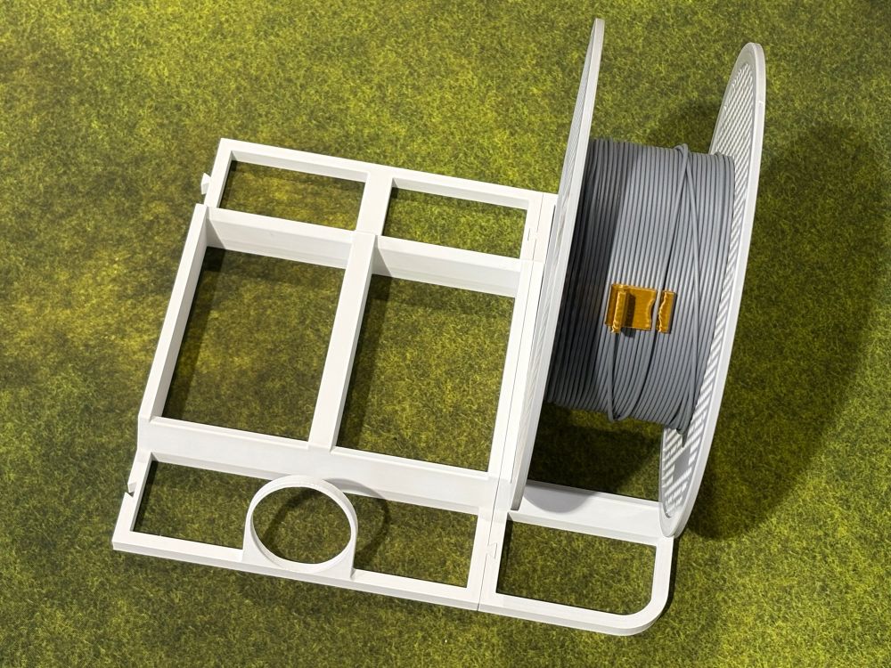 A 3d printed plastic frame with holes for seating plastic filament spools.  There’s an additional hole in the center for a hygrometer.