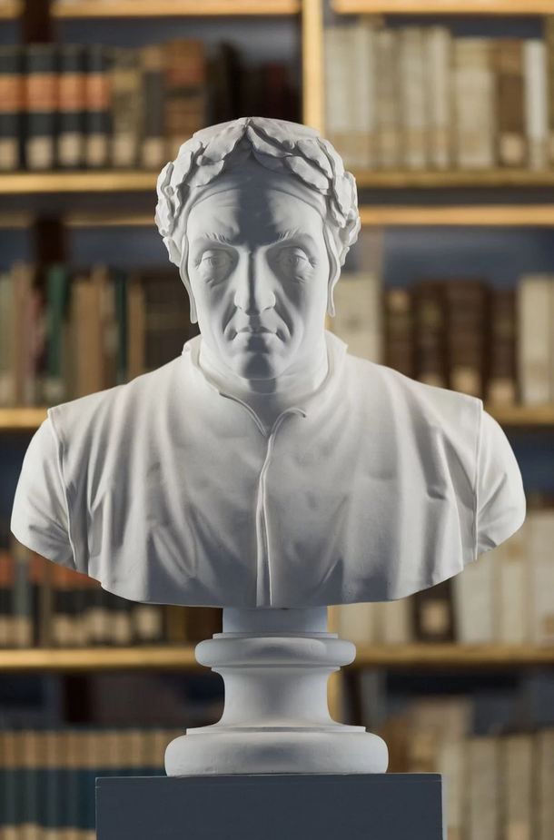 Foto einer Büste von Dante Alighieri im Rokoko-Saal der Herzogin Anna Amalia Bibliothek. Im Hintergrund verschwommene historische Bücherregale.