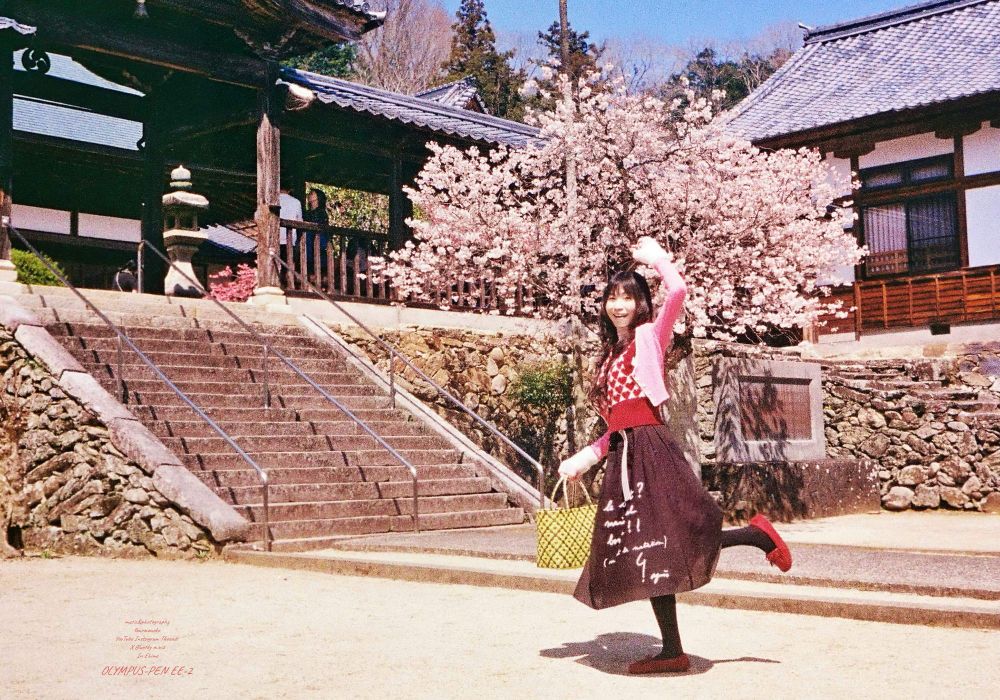 OLYMPUS-PEN EE-2でのフィルム写真 お寺の早咲の桜の前で嬉しいポーズの女性
