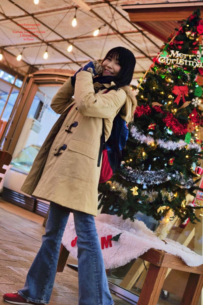 愛媛県内の道の駅で　クリスマスツリーの前で喜びのポーズをする女性