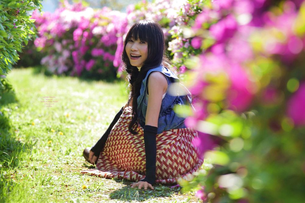山の景色が美しいツツジ 咲く公園のツツジ の小道に座りこちらを見る女性