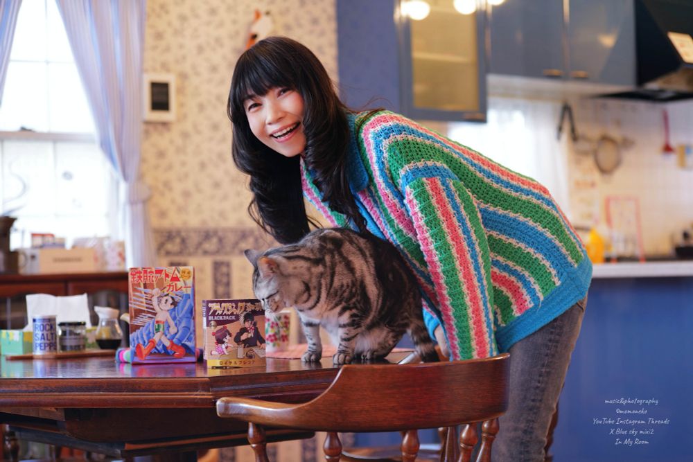 お土産のアトムカレーとブラックジャック珈琲を見る猫と女性