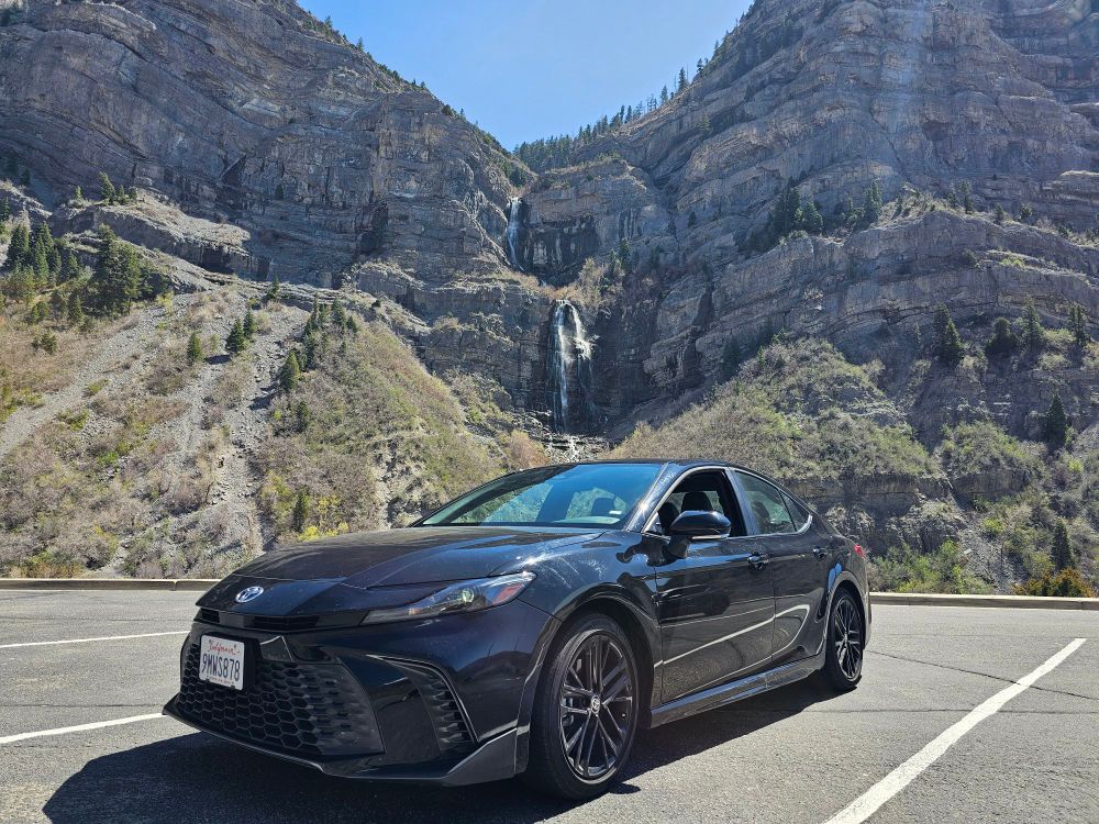 Black 2025 Toyota Camry in front of a waterfall