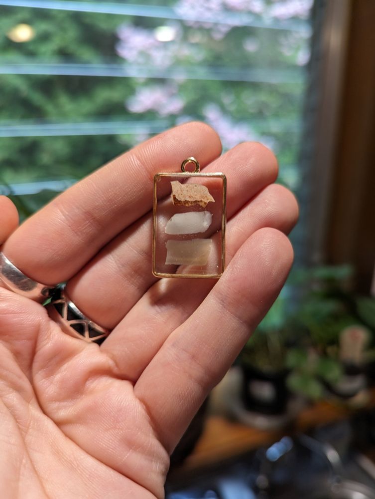 Three flakes, Keokuk, Novaculite, and Flint River, in resin in a gold colored rectangular pendant.