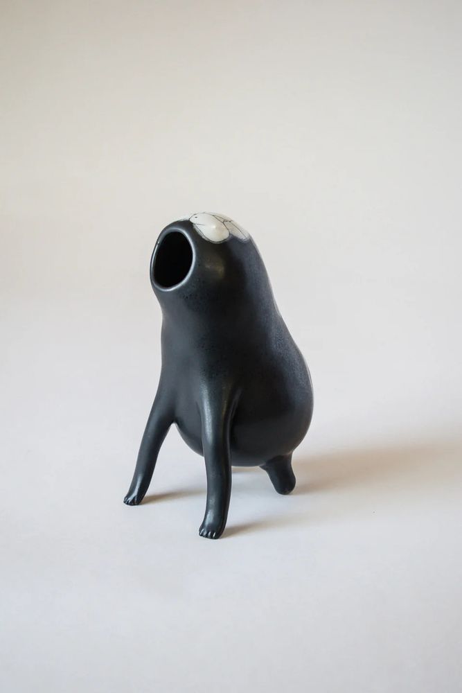 A black and white ceramic incense burner. It's called an Encrusted Voidling.. It has a long front legs, and small mouth shaped opening aimed at the sky