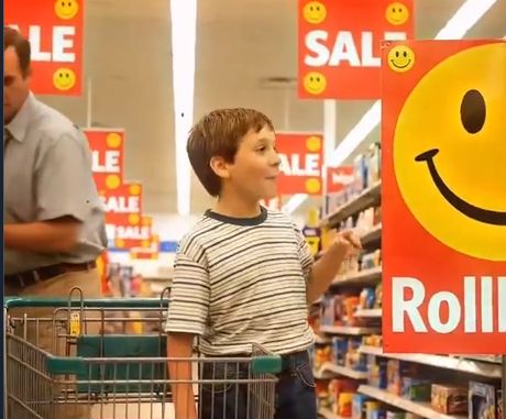 A still image from the quoted AI-generated video showing a shopping cart simultaneously existing in the same physical space as a child.