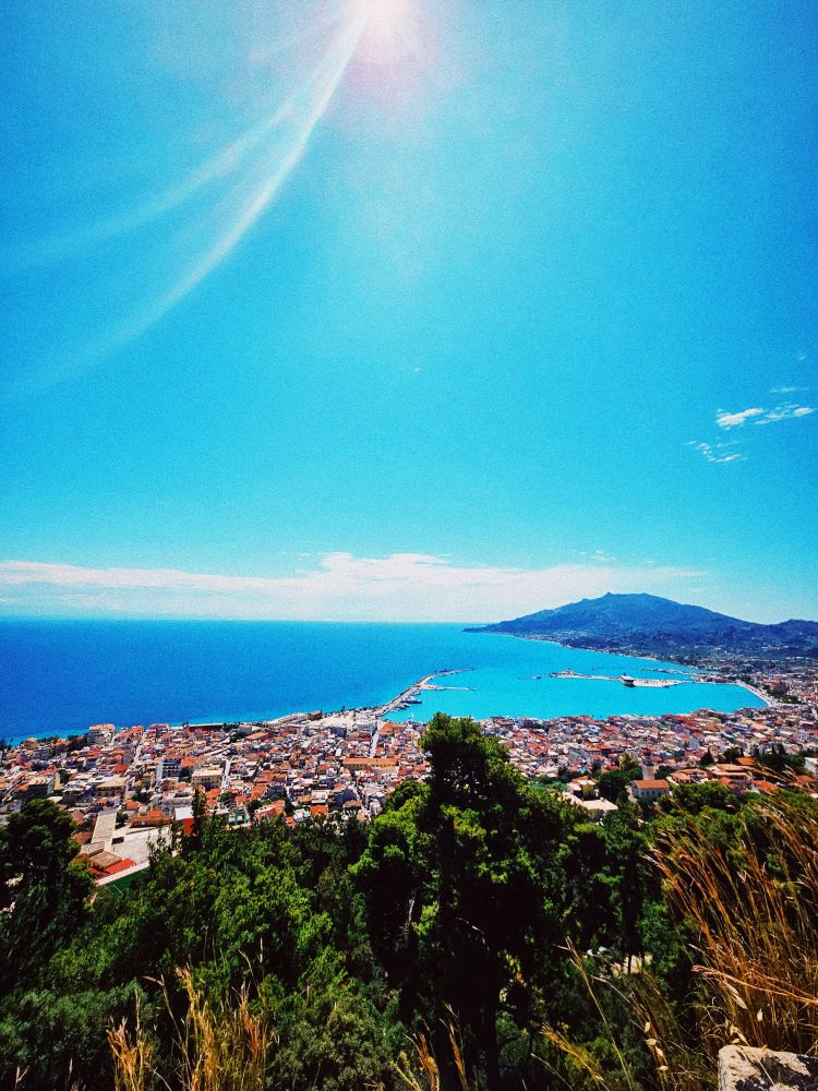 View of the island of Zakynthos from the top of a hillside on a sunny day with bright blue sky.
