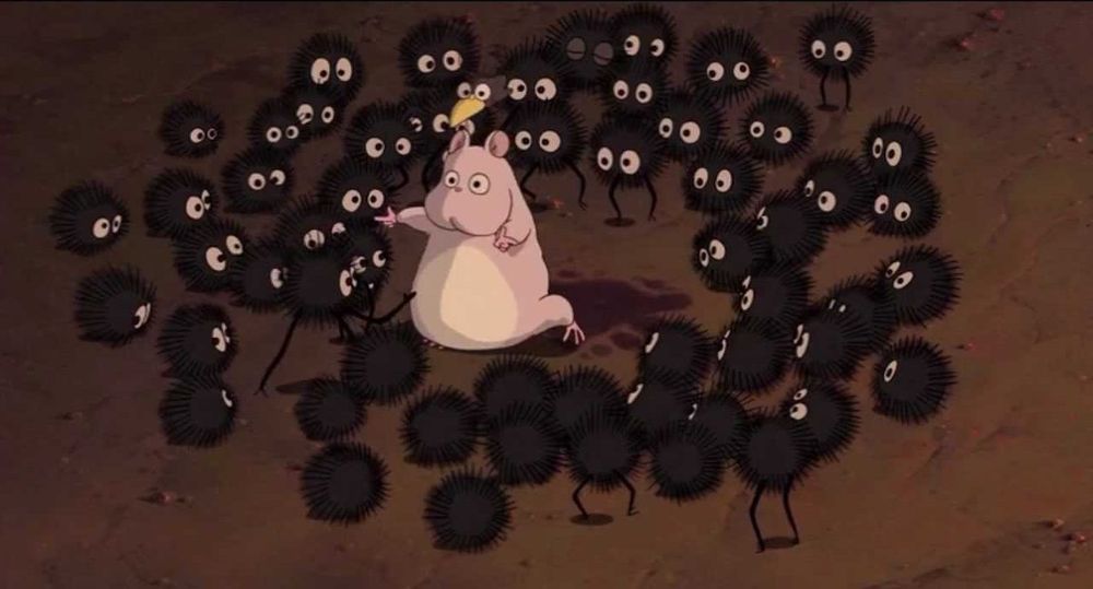 A set of small furry round guys gathered around a mouse from the movie Spirited Away
