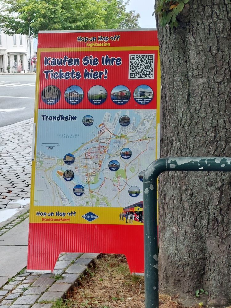 Ein Werbeschild für eine Hop on Hop Off Tour in Trondheim, auf Deutsch geschrieben 