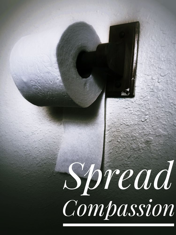 Toilet paper roll placed incorrectly on the dispenser with the words “Spread Compassion.”