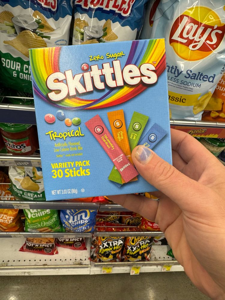 Photo of a box of “zero sugar skittles tropical artificially flavored low calorie drink mix variety pack, 30 sticks.” box is light blue and features the skittles logo with four sachets in pastel colors.