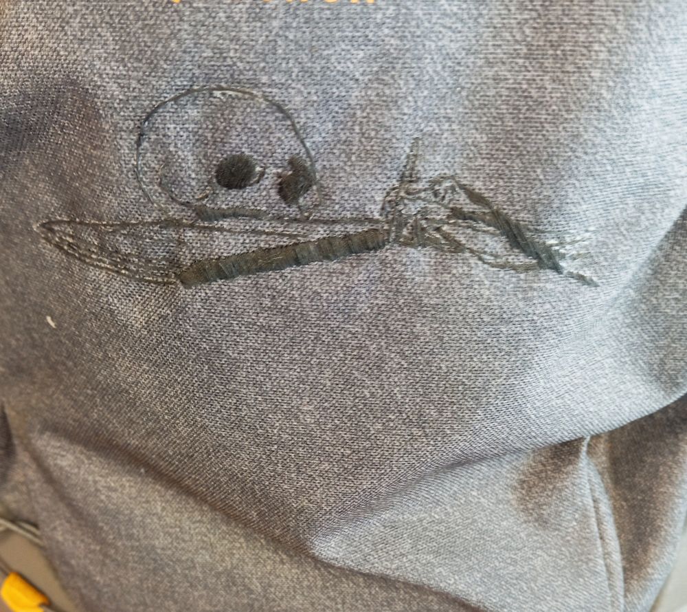 Photo rapprochée de la face avant de mon sac sur lequel on voit une broderie au fil noir reproduisant les contours de la main, du livre et du crâne du tableau précité (Jérôme de Stridon par Le Caravage)