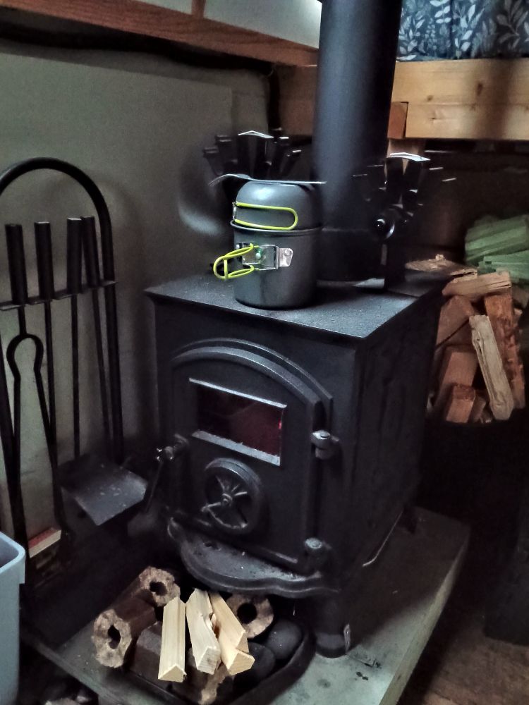 Log burner with a pot of lentil and tomato soup slowly cooking