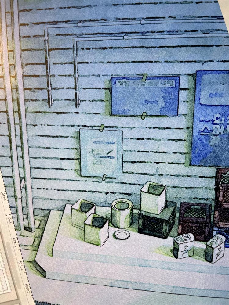This image shows a detailed background scene from a comic panel. It depicts the corner of an exterior wall, drawn in a painterly, watercolor-like style with blue and green tones. The wall is covered in horizontal planks with some exposed pipes running vertically and then bending horizontally near the top left. A few posters or signs are taped to the wall, one above the other. At the bottom, there is a raised concrete ledge that functions as a small platform or shelf. On it are various containers and objects: • Several square trash bins or crates stacked together. • A round can or bucket and a small circular dish. • Two jerrycans with markings on them, placed near the right side. • Stacked plastic or wooden crates in darker tones, adding texture. The whole scene has the look of a quiet back alley or storage area, with muted lighting and a damp, slightly grimy atmosphere.