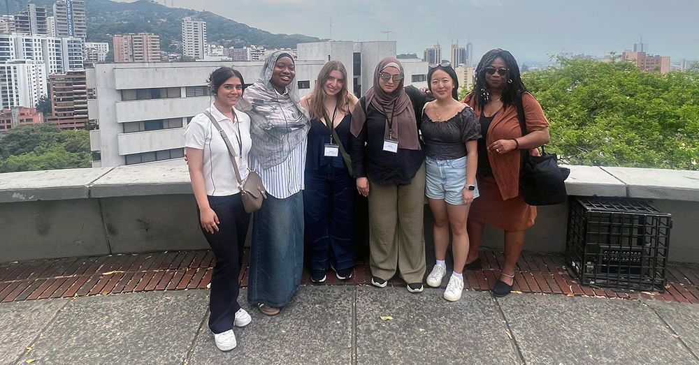 A group of students posing on a rooftop balcony 
