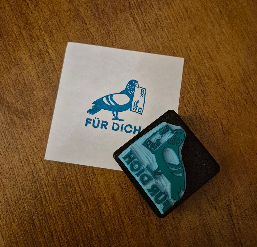 A carved rubber stamp and its print of a pigeon holding a letter in its beak. Underneath the stamp says "Für dich" ["for you"]. 
