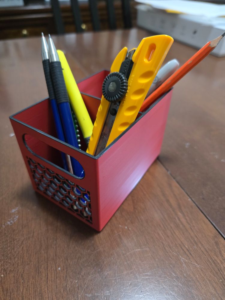 A 3D printed stationery holder inspired by the Milwaukee hardware colors. It is filled with various stationery.