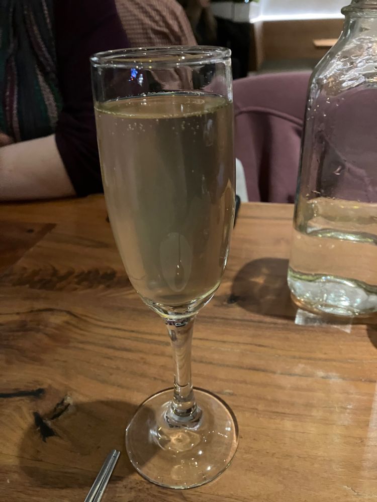 A champagne flute on a wooden table top, a delicious lychee cocktail 