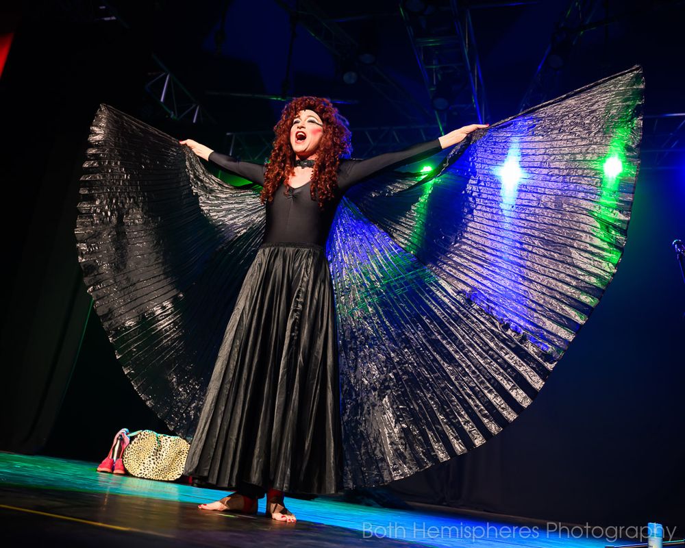 A woman stands with cape spread wide in Evening Without Kate Bush at The Astrolabe 