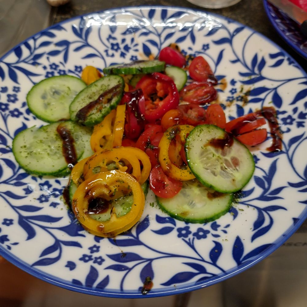 Weiß-Blauer Teller Gurke, Tomate und Spitzpaprika gewürzt mit Olivenöl, Balsamiko und Kräuterlingen.