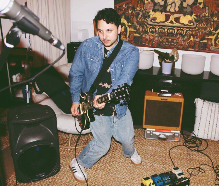 James playing guitar in the classic “Disney knees” position at a SH!NER rehearsal