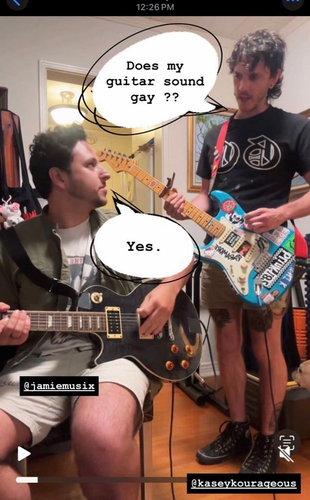 Kasey + James at band practice. James sitting down with his guitar looking at Kasey standing beside him with his guitar. Text bubble from Kasey say “does my guitar sound gay?”, text bubble from James says “yes.” 🖤 SH!NER is a queer alternative rock back in LA 