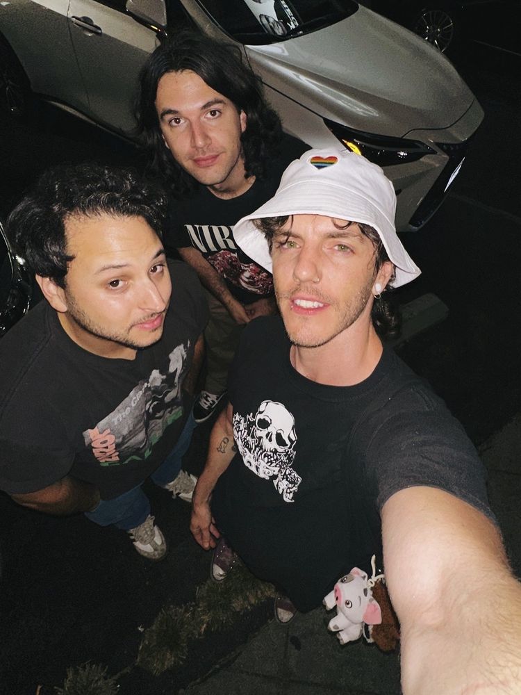 Selfie of James, Jesse, + Kasey in a diner parking lot. Each wearing a t-shirt. 