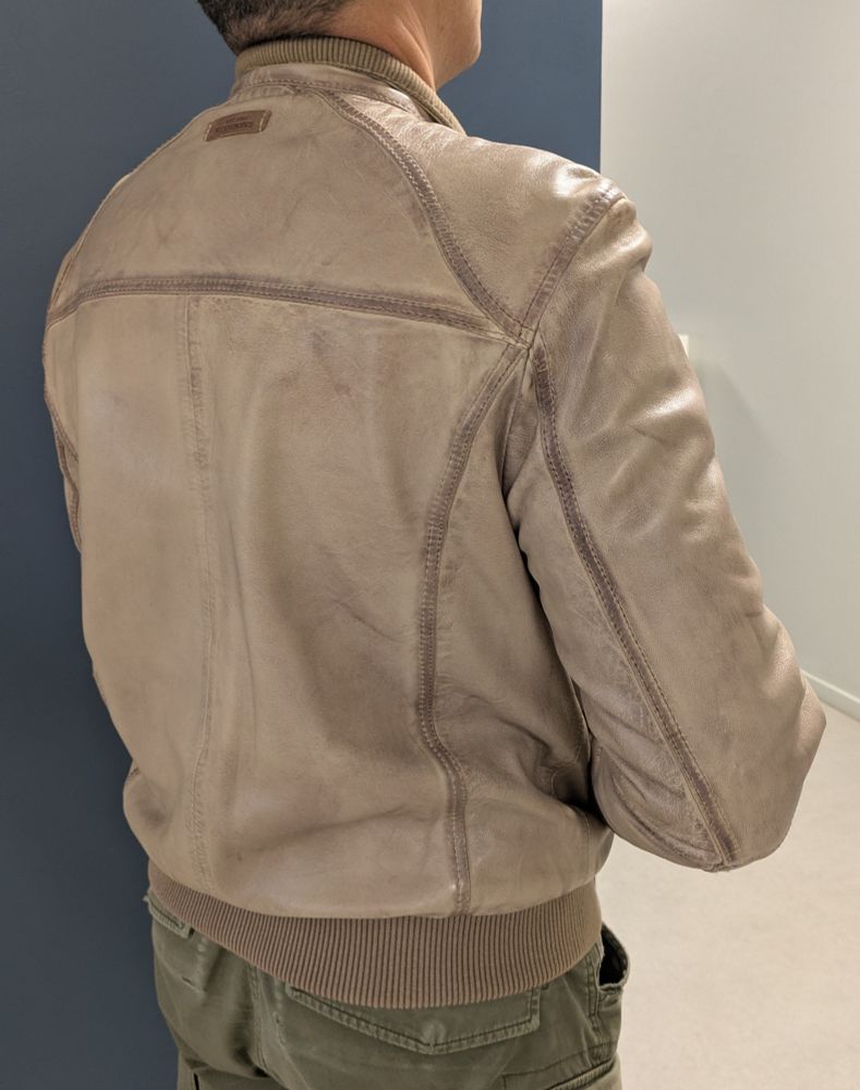 Une veste en cuir beige de très bonne facture portée par un homme élégant a qui elle va très bien, vu de 3/4 dos