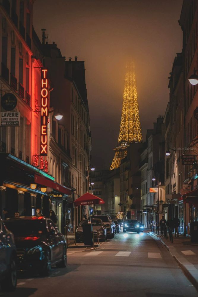Paysage parisien, une rue avec l'établissement Thoumieux et la tour Eiffel au fond dans la brume...