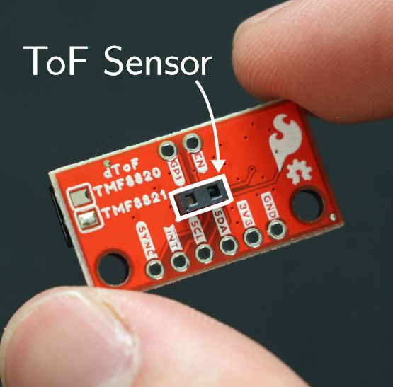 Image of AMS TMF8820 ToF sensor held between two fingers. The sensor is roughly the size of a grain of rice.
