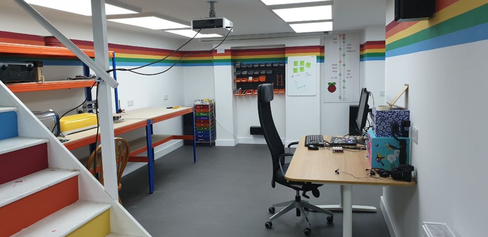 a clean basement with a desk and workbench. the colour scheme is rainbow