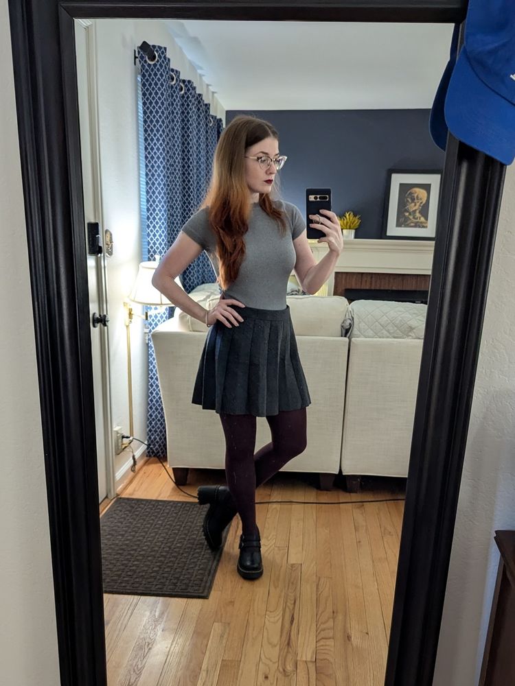 mirror selfie of me wearing glasses, a gray shirt, gray skirt, maroon tights, and black mary janes. i have no facial expression and i am gorgeous.