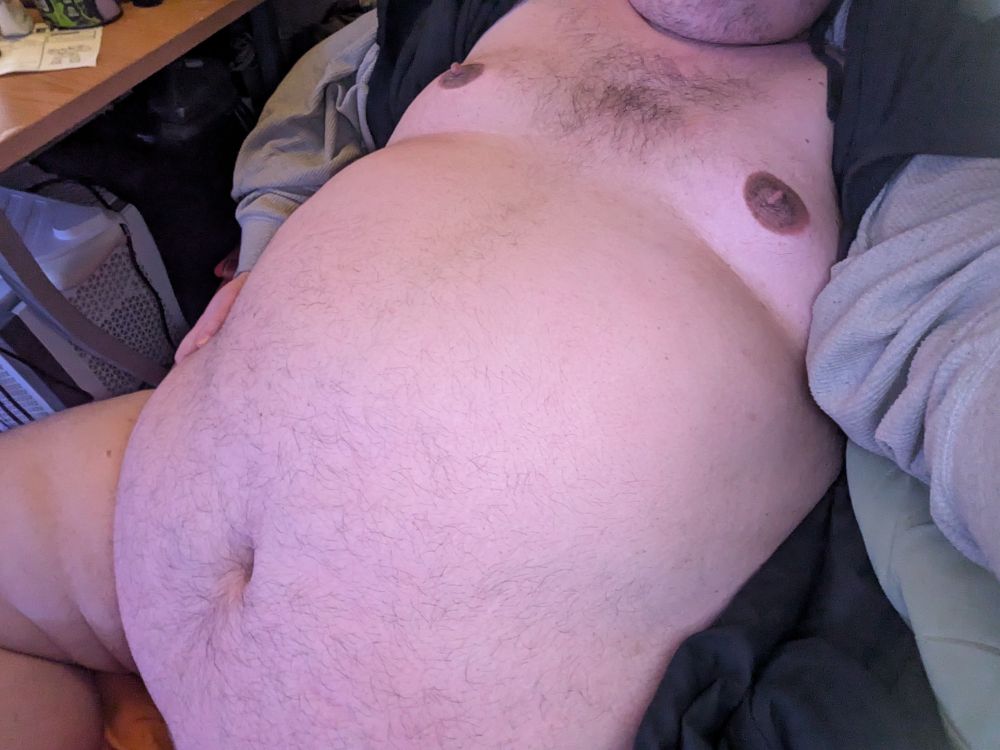 My belly is shown while reclining, mostly smooth but with a sparse spray of hair. My chest has a dark tuft in the middle. My hoodie is pulled over my head so you can't see my face.