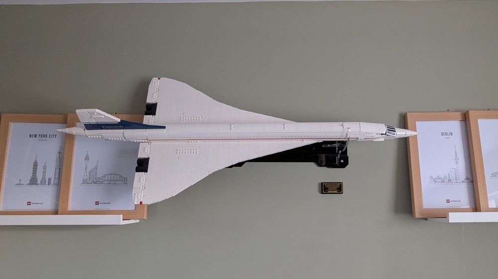 Lego Concorde model wall mounted in a sage green room with framed schematic posters of LEGO skylines