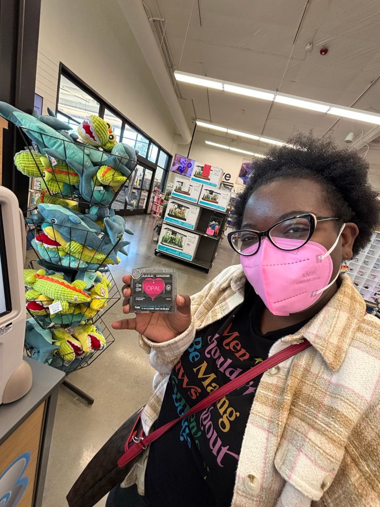 Jasmine wearing a pink KN95 mask while holding an engraved dog tag at Petco