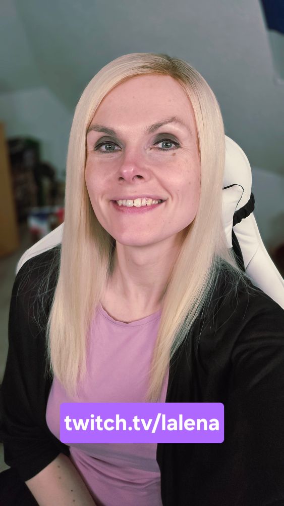 Lena lächelnd in ihrem Zimmer sitzend. Sie trägt ein rosa Shirt und einen schwarzen Bolero darüber.