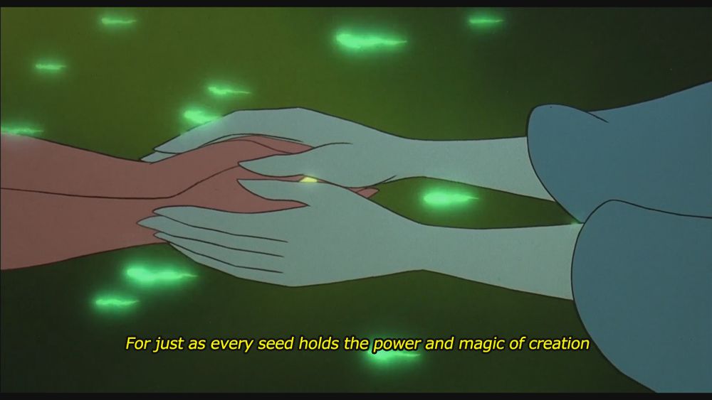 Screenshot from the 1992 animated film Ferngully: The Last Rainforest. There is now a close-up of the fairy's hands. The aged fairy continues: "For just as every seed holds the power and magic of creation..."