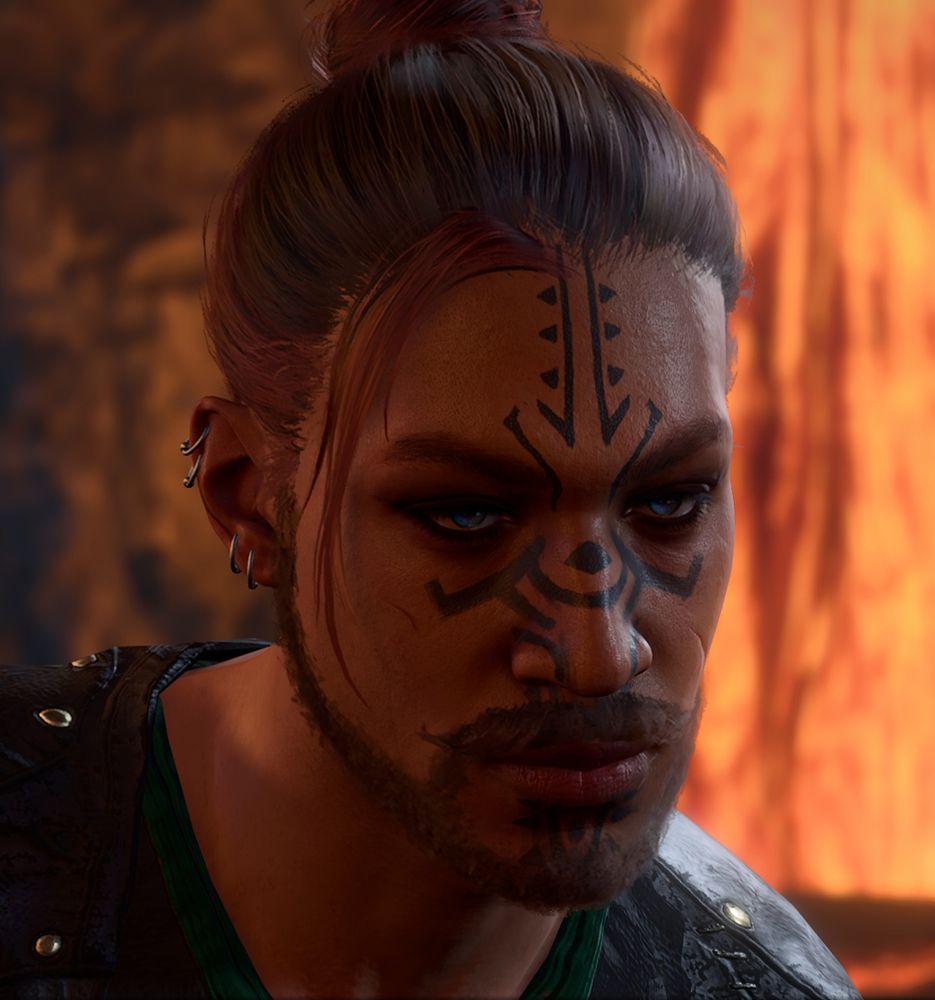 Game screenshot of a handsome man with dark brown hair tied up in a bun with fading pink highlights. He has a tattoo on his face, blue eyes and a growing beard and mustache. He also has several piercings.