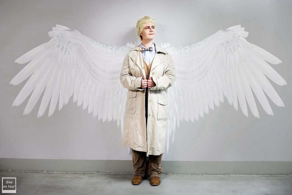Cosplay Aziraphel from Good Omens standind in front of a white wall with angel wings and a halo