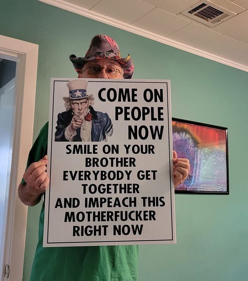 Man holds a sign that reads: COME ON PEOPLE NOW SMILE ON YOUR BROTHER EVERYBODY GET TOGETHER AND IMPEACH THIS MOTHERFUCKER RIGHT NOW