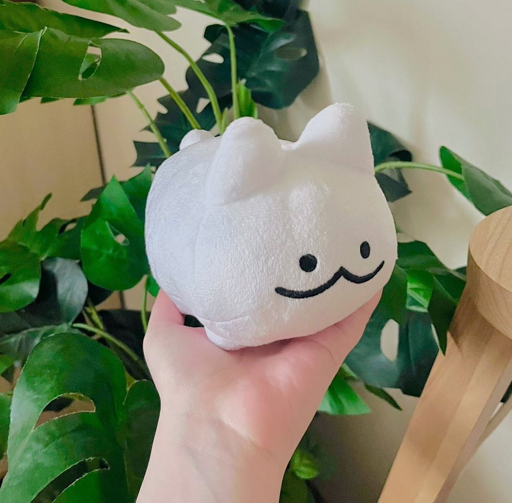 a little white cat plush with a cute smiling face. 